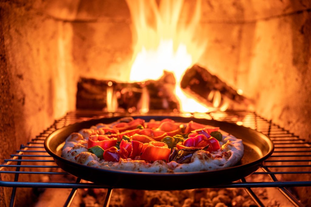 Pizza Ovens Have Grown Up, And They Are No Longer Just a Summer Novelty Pizza baking in a wood fired garden pizza oven